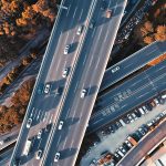 High-altitude view of a highway intersection with moving vehicles and surrounding greenery.